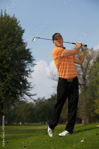 Young man swinging golf club