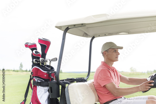 Middle-aged man driving golf cart at course