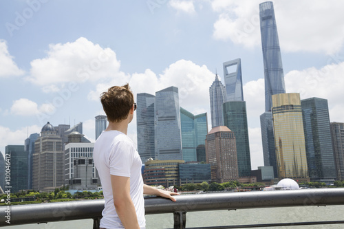 Side view of man looking at Shanghai World Financial Center against cloudy sky