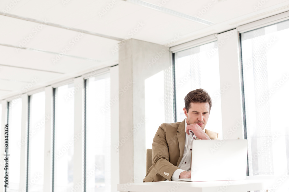 Young businessman using laptop at desk in new office Young businessman using laptop at desk in new office