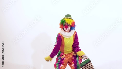 Funny female clown having fun while dancing actively holding harmonica