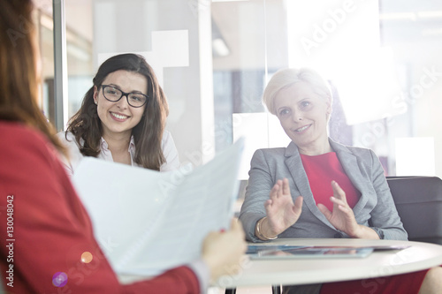 Mature businesswoman with female colleagues discussing at table in office