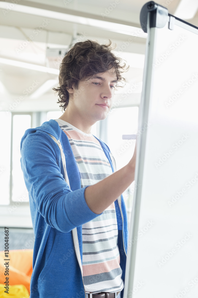 Young businessman writing on presentation board in office Young businessman writing on presentation board in office