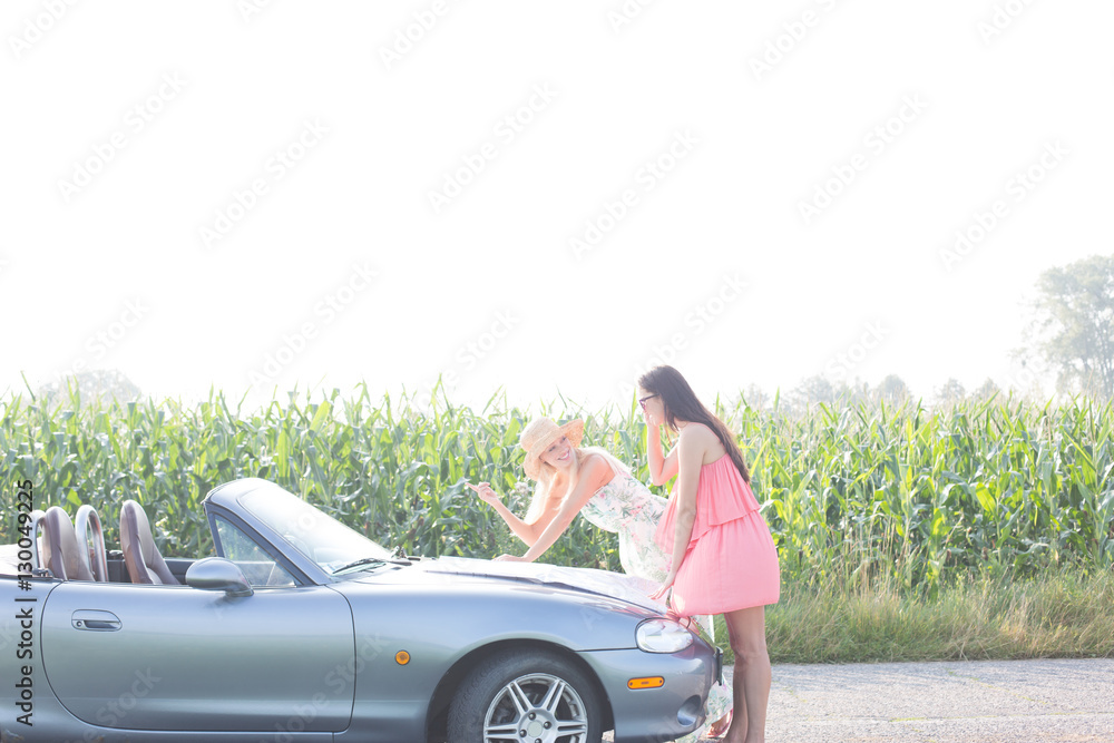 Women reading map on convertible at countryside
