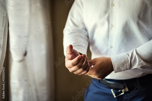 Businessman dress shirt. The man in the white shirt in the window dress cufflinks. Politician, man's style, Businessman buttoning his shirt,male hands closeup, American, European businessman