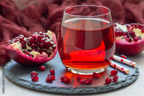 Pomegranate drink in glass and fruit on background, closeup, horizontal