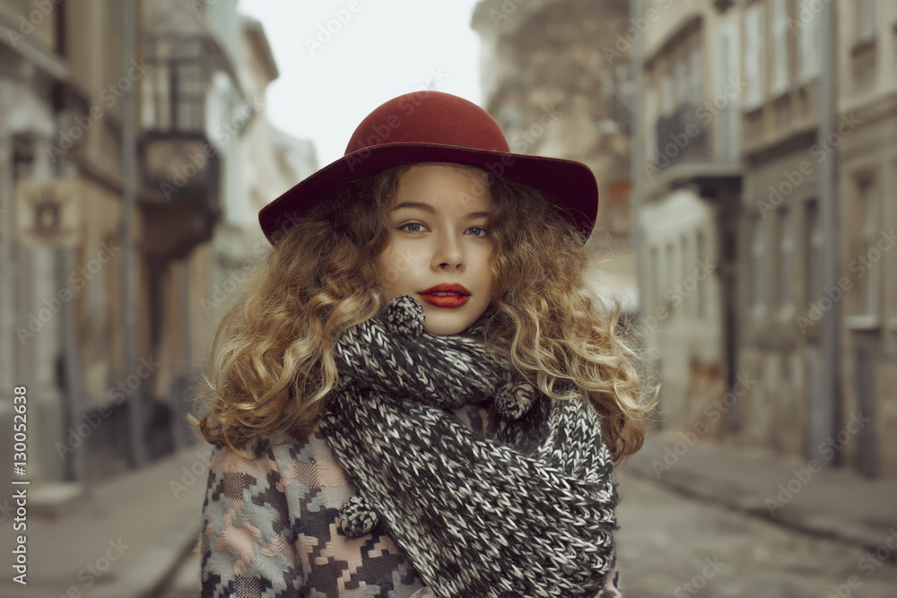 Model in red hat and scarf posing at the street