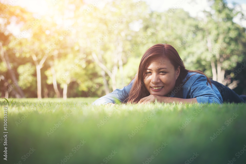 Charming smiling young hipster woman lying on green grass. Charming smiling young hipster woman lying on green grass.