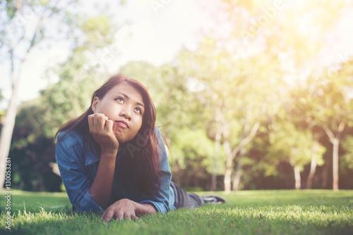 Charming smiling young hipster woman lying on green grass.