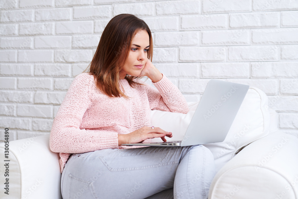 A serious-minded woman sitting comfortably and holding a laptop A serious-minded woman sitting comfortably and holding a laptop