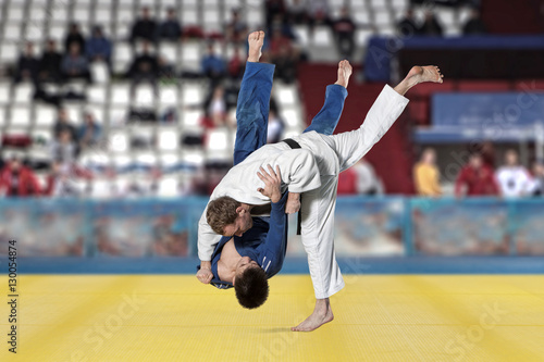 Judokas fighters fighting men on fans background