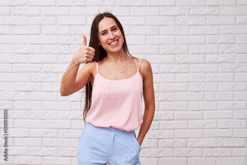 Carefree positive longhaired brunette holding thumbs up over whi