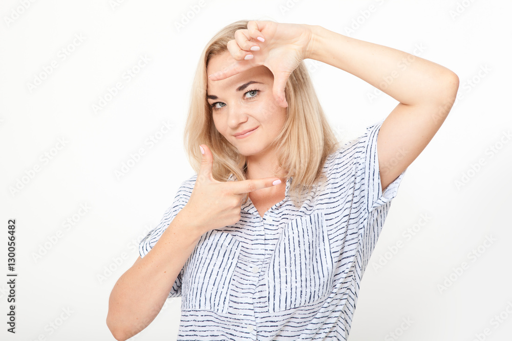 Gesturing finger frame. Beautiful young blond hair woman looking at camera and gesturing finger frame while standing against white background Gesturing finger frame. Beautiful young blond hair woman looking at camera and gesturing finger frame while standing against white background
