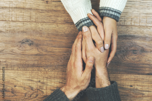 man and a woman holding hands at a wooden table photo