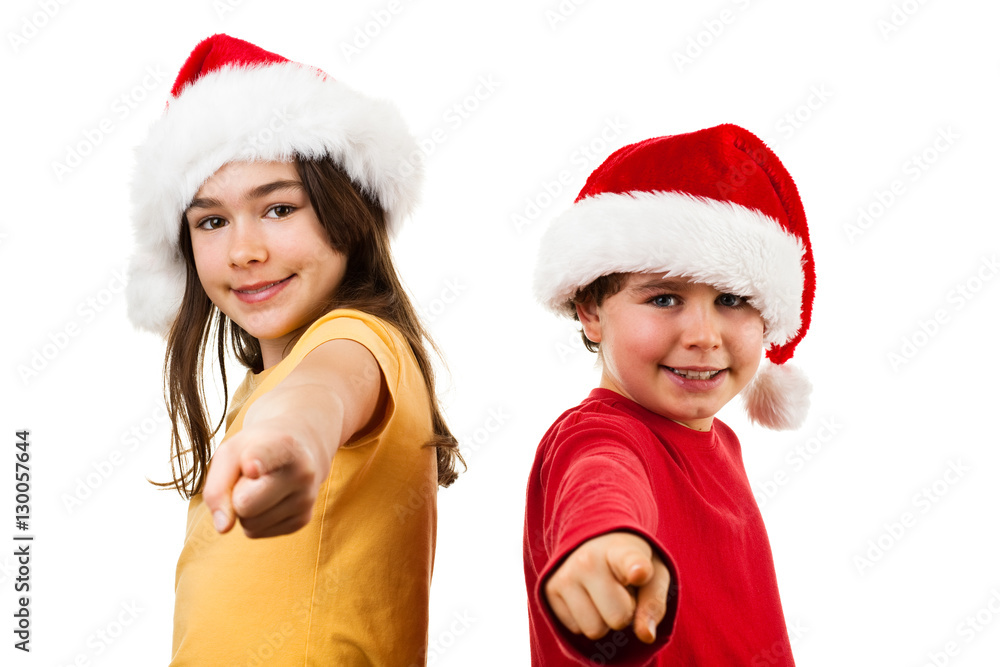 Christmas time - girl and boy with Santa Claus Hat pointing Christmas time - girl and boy with Santa Claus Hat pointing