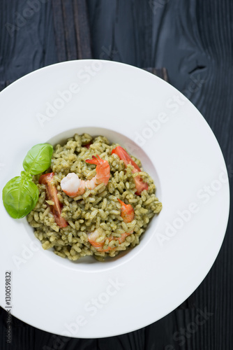 White plate with spinach risotto, overhead view, studio shot