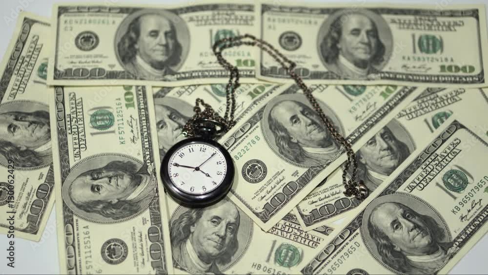 Time is money - a pocket watch on a background of one-hundred dollar bills Time is money - a pocket watch on a background of one-hundred dollar bills