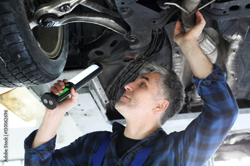 Mechanik, mężczyzna naprawia samochód.Samochód w warsztacie, mechanik sprawdza stan podwozia.