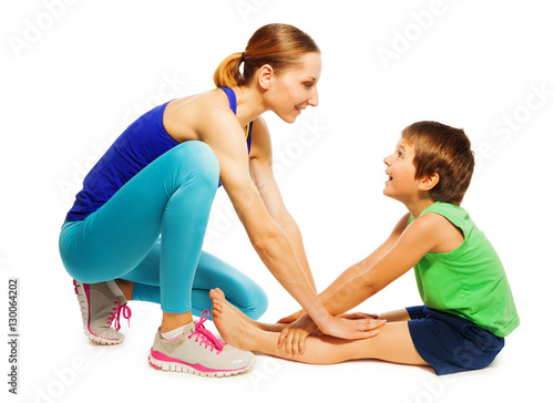 Female trainer teaching kid boy stretching muscles photo