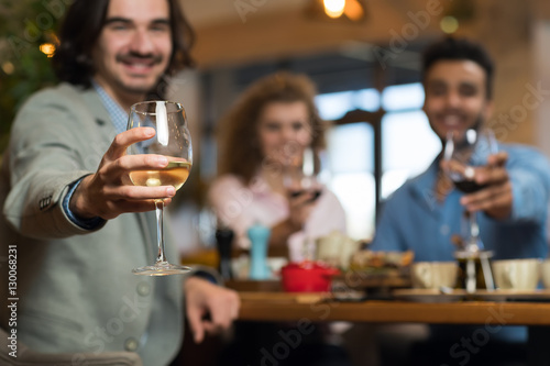 Young Business People Group Drink Wine Sitting Restaurant Table  Friends Hold Glasses Toasting Smiling Mix Race Men Women