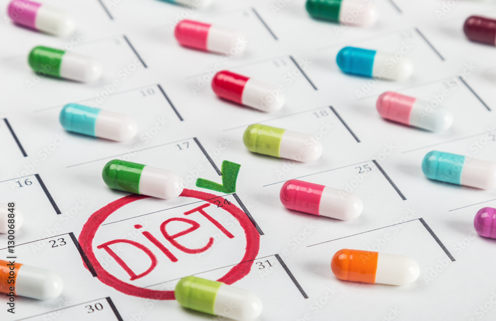pills of different colors lie on the diet plan. Schedule of pills. Focus on the word diet pills of different colors lie on the diet plan. Schedule of pills. Focus on the word diet