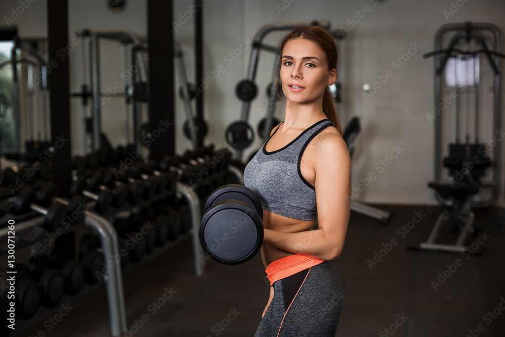 Fototapeta premium Woman doing exercises with dumbbells in the gym