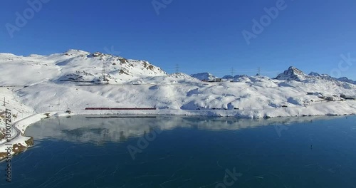 Aerial 4k - Bernina Express - Passo del Bernina - Vista aerea del trenino rosso e del lago Bianco ghiacciato con pattinatori