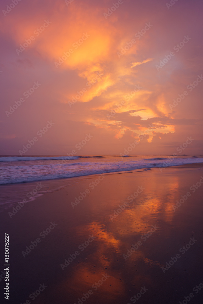 Sunset clouds and waves on empty beach