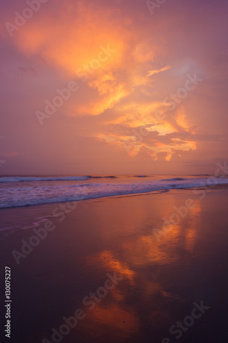 Sunset clouds and waves on empty beach