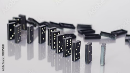 Curved line of dominoes falling in sequence, domino effect, reflective surface, mechanical effect, games. Close up, slow motion.