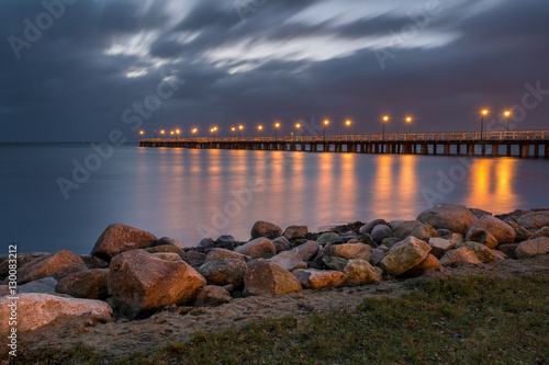 Seascape of coastline with illuminated pier in Gdynia Orlowo at night. Poland