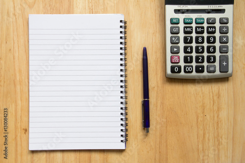 Blank paper note book with pen, calculator on wood table
