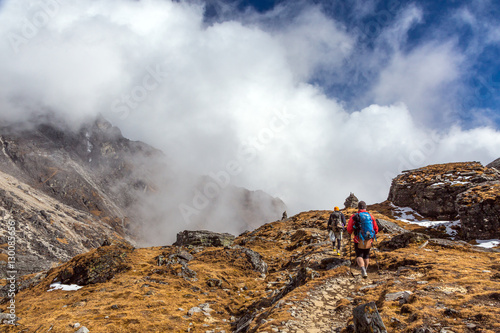Mountain Hikers walking on grassy Terrain beautiful Clouds