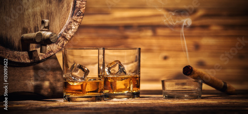 Canvas Print Glasses of whiskey with ice cubes served on wood