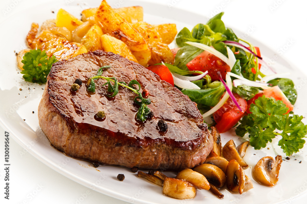 Grilled steak, baked potatoes and vegetable salad on white background 