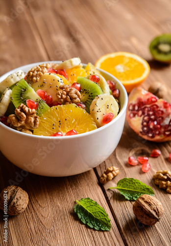 Healthy fruit salad made of orange, kiwi, banana, walnuts, pomegranate and chia seeds
