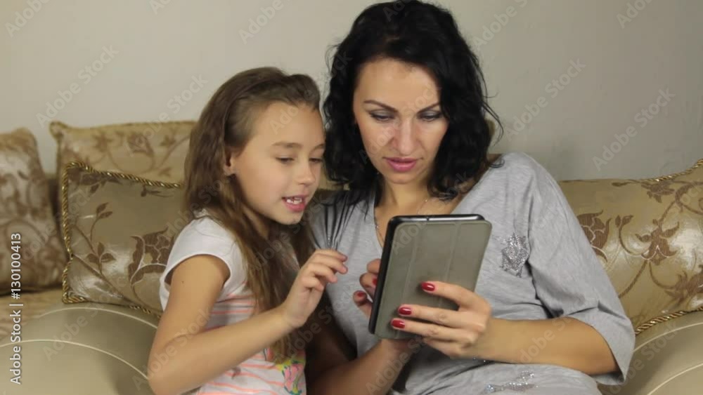 Daughter teaches mother to play the game on the tablet. Daughter teaches mother to play the game on the tablet.