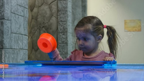 little girl playing air hockey