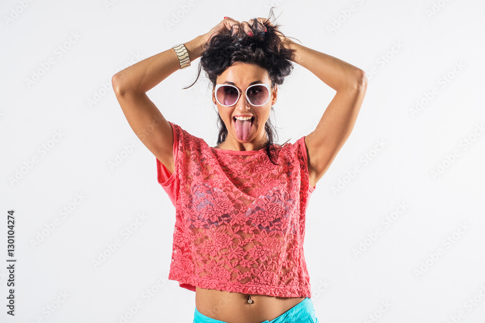 Studio portrait of a playful girl having fun, wearing sunglasses and trendy summer outfit.