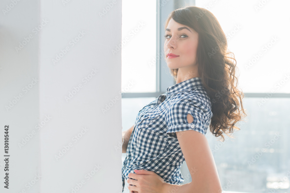 Young attractive model with fit body posing in light studio, wearing jeans and blue checkered shirt, standing sideways. Young attractive model with fit body posing in light studio, wearing jeans and blue checkered shirt, standing sideways.