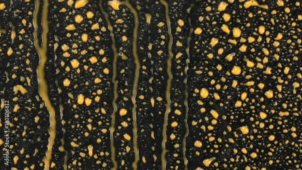 Abstract background. Yellow paint flowing streams on a black surface. Abstract background. Yellow paint flowing streams on a black surface.