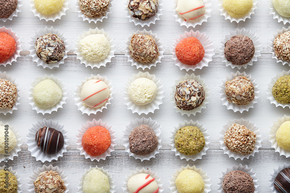 Chocolate truffle candies arranged in rows on white wooden background Chocolate truffle candies arranged in rows on white wooden background