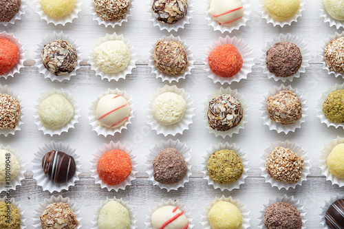 Chocolate truffle candies arranged in rows on white wooden background