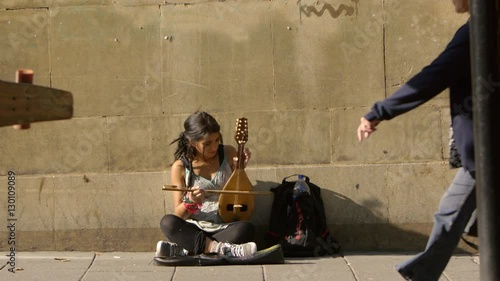 female beggar street artist playing on the sidewalk photo