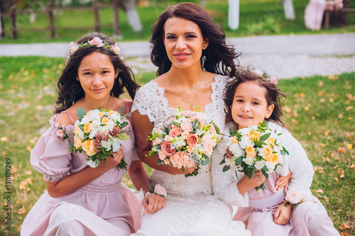 Cute little bridesmaids holding bouquet in lawn with Bride.