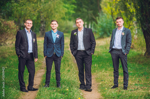 Personable groom with best mans or groomsman posed on park at wedding day.