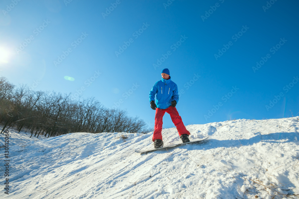 Snowboarder is riding downhill in winter forest