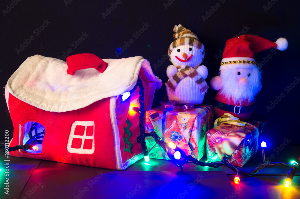 Новогодний Санта Клаус и снеговик рядом с домиком на тёмном фоне. Празднование Нового года. 
