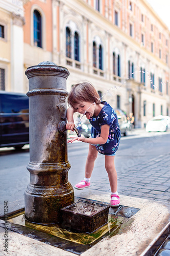 Photography Funny girl drinks water from a fountain in Rome.