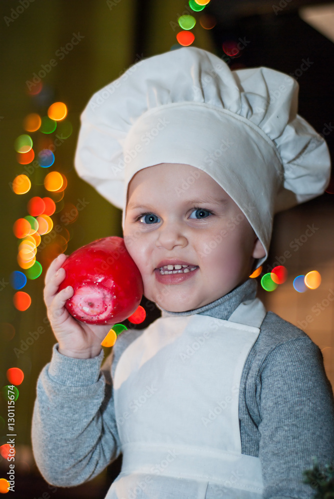 Little girl dressed as a cook pressed to his cheek red candle Little girl dressed as a cook pressed to his cheek red candle